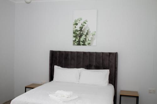 a bed with white sheets and a plant above it at Moxwini Self Catering Apartments in Maun
