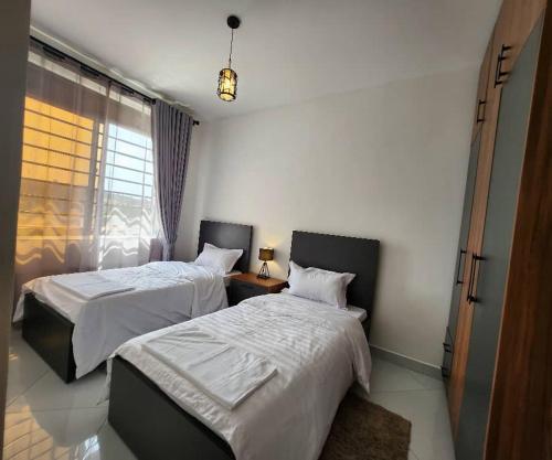 Kampala Apartments في كامبالا: غرفة نوم بها سريرين ونافذة