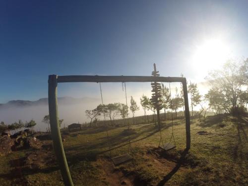 a swing in a field with the sun in the background at El Pueblito Hotel Boutique in Samaipata