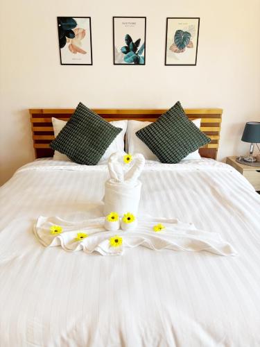 a bed with white towels and yellow flowers on it at Sachi Home Villa Bangtao - Near Muay Thai and Beach in Ban Thalat Choeng Thale