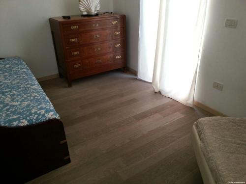 a bedroom with a dresser and a bed and a wooden floor at Clelia Apartments - Deiva Marina in Deiva Marina