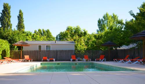 una piscina con sillas y sombrillas junto a una casa en Camping les Fouguières, en Carcès