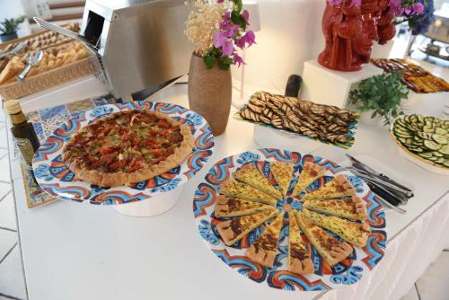 a table topped with plates of food and pies at Pietra Pomice Hotel in Lipari
