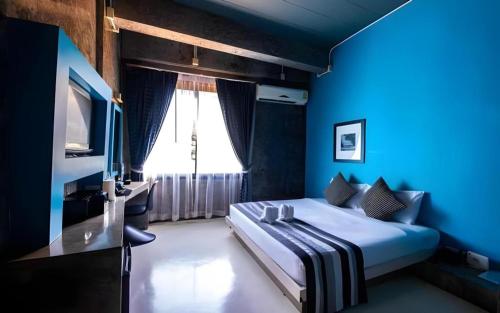 a blue bedroom with a bed and a television at The B Ranong Trend Hotel in Ranong