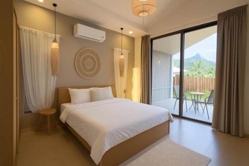 a bedroom with a white bed and a balcony at Cocolane Villa 2 in Ban Madua Wan