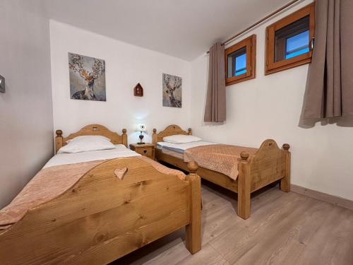 two twin beds in a room with two windows at Résidence Grand Bois A1124 Clés Blanches in La Tania