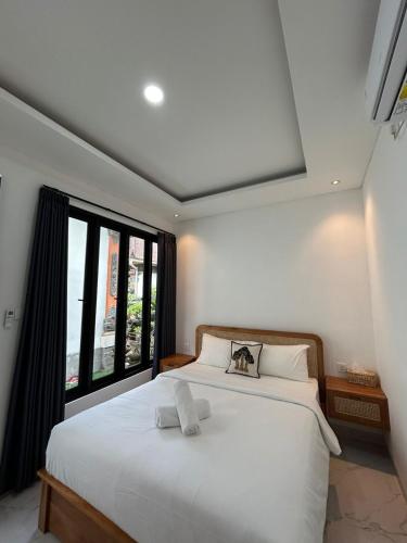 a bedroom with a large white bed and a window at Kariarta Homestay in Cemagi