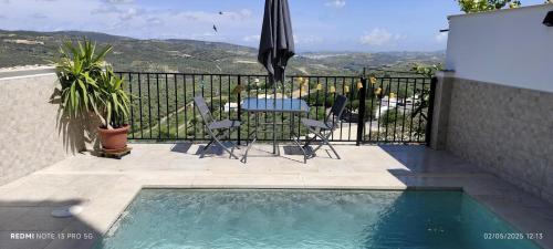 un patio con mesa, sombrilla y piscina en Casa Rural Emma, en Zuheros