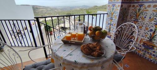 una mesa con un plato de fruta y zumo en el balcón en Casa Rural Emma, en Zuheros