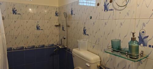 ein Badezimmer mit Toilette und gefliester Wand in der Unterkunft Amore Holiday Home in Canacona