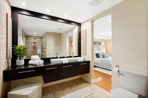 a bathroom with a sink and a large mirror at The Coastal Duo Escape in West Palm Beach