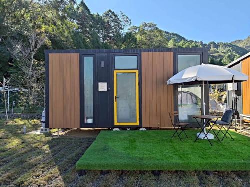 a tiny house with a table and an umbrella at Forest Star Cottage X by Tiny Away in Hsin-ch'eng