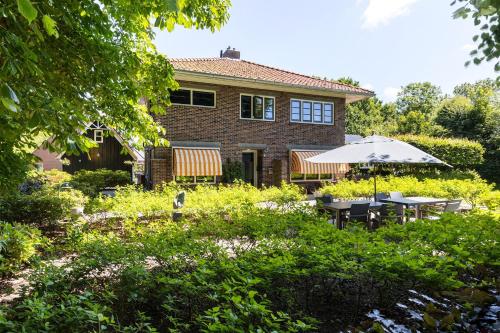 a house with a garden with tables and an umbrella at B&B - Sauna D'Olle Pastorie in Vierhuizen