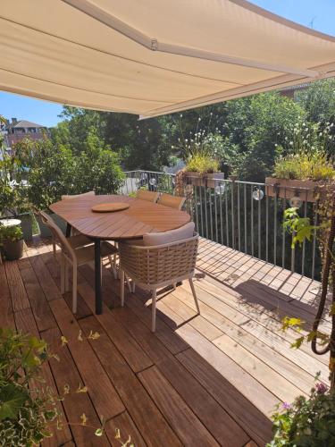 una terraza de madera con mesa y sillas bajo una sombrilla en Sarre-Ulysse Refined apartment in Sarreguemines, en Sarreguemines