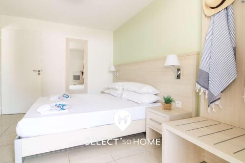 ein Schlafzimmer mit einem weißen Bett und einem Spiegel in der Unterkunft SELECT'soHOME - Résidence Le Poséidon - Piscine & Parking - Appartement pour 4 personnes - POS03 in Bormes-les-Mimosas