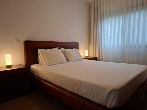 Un dormitorio con una cama con sábanas blancas y una ventana. en Sítio da Assumada, en Faja Grande