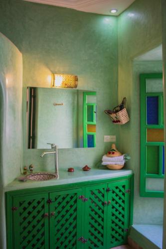 a green bathroom with a sink and a mirror at Riad ELJazouli in Marrakesh