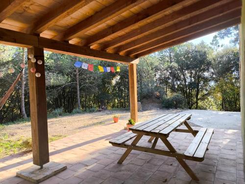 a wooden picnic table on a patio with a wooden roof at La Coma in gualba de Dalt