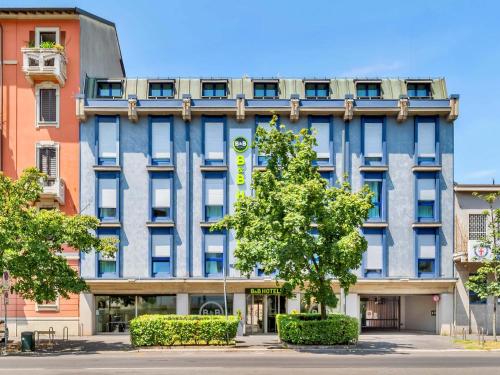 um prédio de apartamentos com uma árvore em frente em B&B HOTEL Milano Portello em Milão