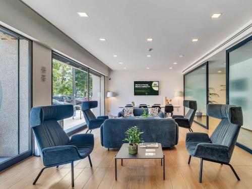 uma sala de espera com cadeiras azuis e um sofá em B&B HOTEL Milano Portello em Milão