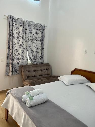 a bedroom with two towels on a bed with a chair at HOTEL POUSADA POR DO SOL in Pato Branco