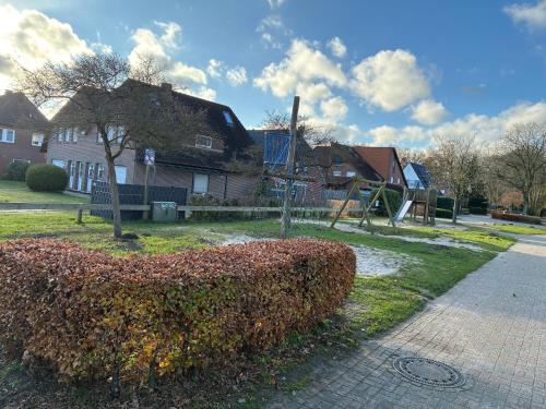 a hedge in front of a house with a playground at Wohnung HaHü in Dangast