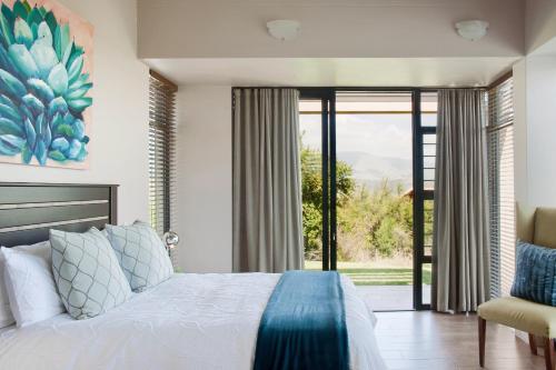 een slaapkamer met een bed en een groot raam bij Dierama Dream Cathkin Estates in Ardmore