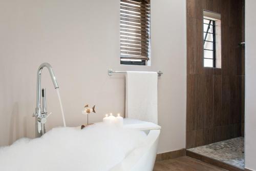 een badkamer met een wit bad en een kaars bij Dierama Dream Cathkin Estates in Ardmore