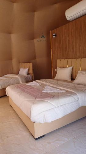 een slaapkamer met twee bedden met witte lakens bij Nadine Luxury Camp in Wadi Rum