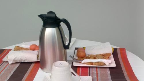 a table with a tea kettle and plates of food at Haven Guest House in Kasese