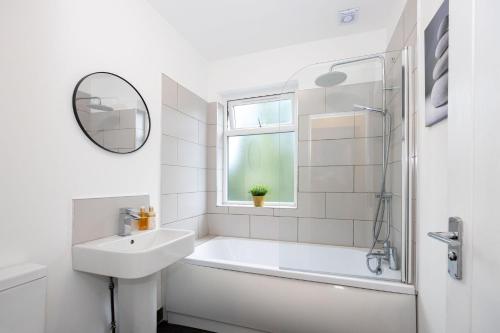 a bathroom with a tub and a sink and a mirror at Stunning 3 Bedroom Home in Newcastle-under-Lyme with Garden in Newcastle under Lyme