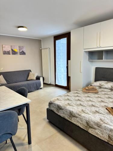 a bedroom with a bed and a table and a couch at Tonale Sweet House in Passo del Tonale