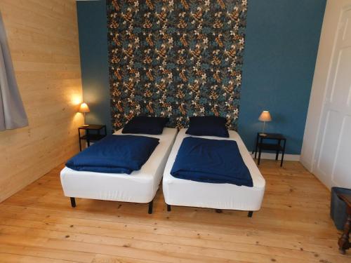 2 letti in una camera con pareti blu e pavimenti in legno di Les Brimbelles a Brû