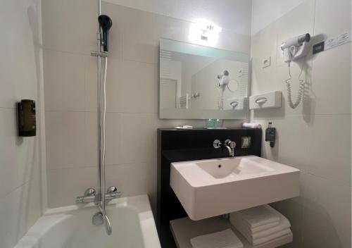a white bathroom with a sink and a shower at Logis Le Gavrinis in Baden