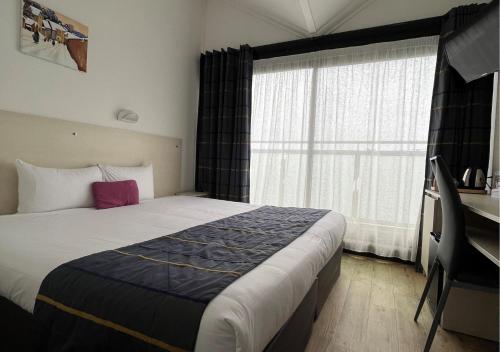 a hotel room with a large bed and a window at Logis Le Gavrinis in Baden