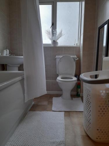 A Four Bedroom House في Tettenhall: حمام به مرحاض وحوض استحمام ونافذة