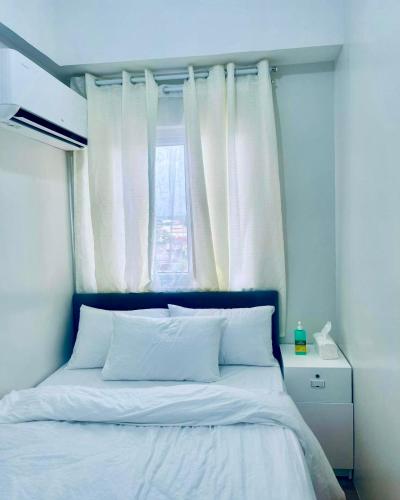 a bedroom with a bed with white sheets and a window at RiverBay 2 BR Apartment Naga City in Naga