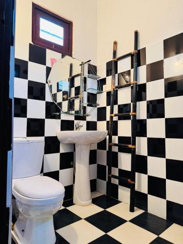 a bathroom with a black and white checkered wall at Paddy View Villa in Pedinnoruwa