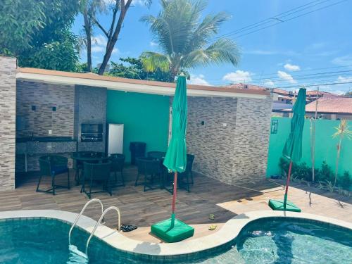 a patio with a pool and a table and umbrellas at La Coruña Flat Makaranduba in Porto De Galinhas