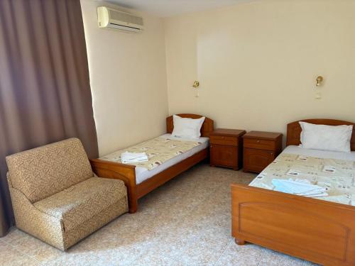 a room with two beds and a chair in it at Family Hotel Chris in Sveti Vlas