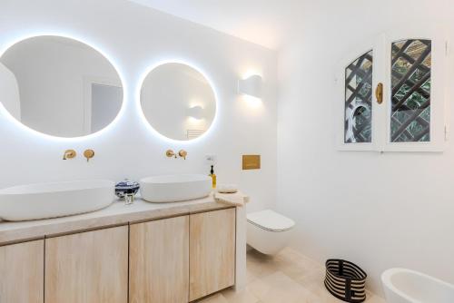 um banheiro com duas pias, um vaso sanitário e dois espelhos em Apartment In Porto Cervo em Porto Cervo
