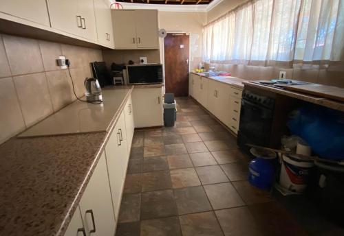 een keuken met witte kasten en een tegelvloer bij Highway Haven in Stilfontein