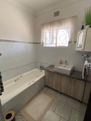 een badkamer met een ligbad en een wastafel bij Highway Haven in Stilfontein
