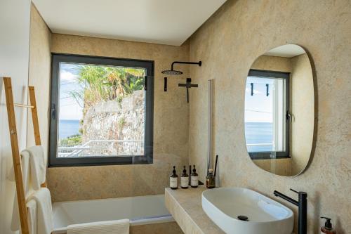 un bagno con vasca, lavandino e specchio di Villa Infinityviews Madeira a Câmara de Lobos