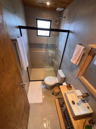 een badkamer met een douche, een toilet en een wastafel bij Cabana Jardim das Nuvens in Urupema