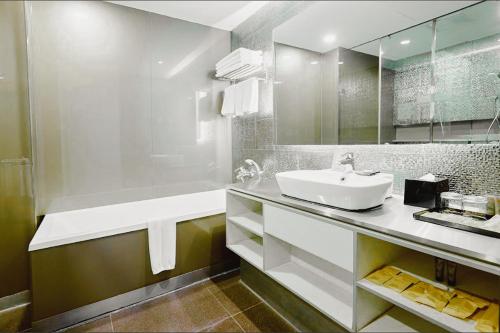 a white bathroom with a sink and a mirror at Vivatel Kuala Lumpur in Kuala Lumpur