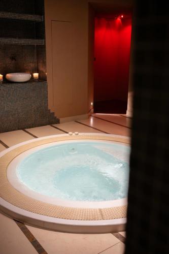 a hot tub in a bathroom with a red wall at Hotel Edelhof in Tarvisio