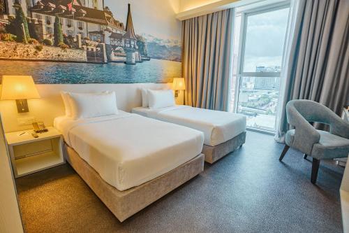 a hotel room with two beds and a chair at Vivatel Kuala Lumpur in Kuala Lumpur