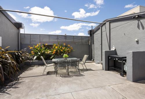 a patio with a table and chairs and a fence at Castle Motel Bairnsdale in Bairnsdale