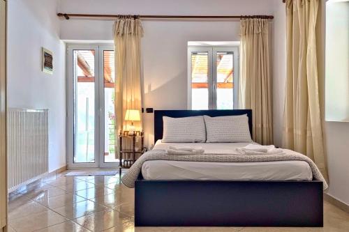 Un dormitorio con una cama grande en una habitación con ventanas. en Demar Rooms & Apartments, en Katakolon